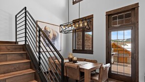 A wooden staircase with a black railing leading to a dining area with a table and chairs.