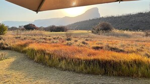 A tented area with a view of a grassy field and distant mountains. - Sofala Lodge (Sterkrivier)