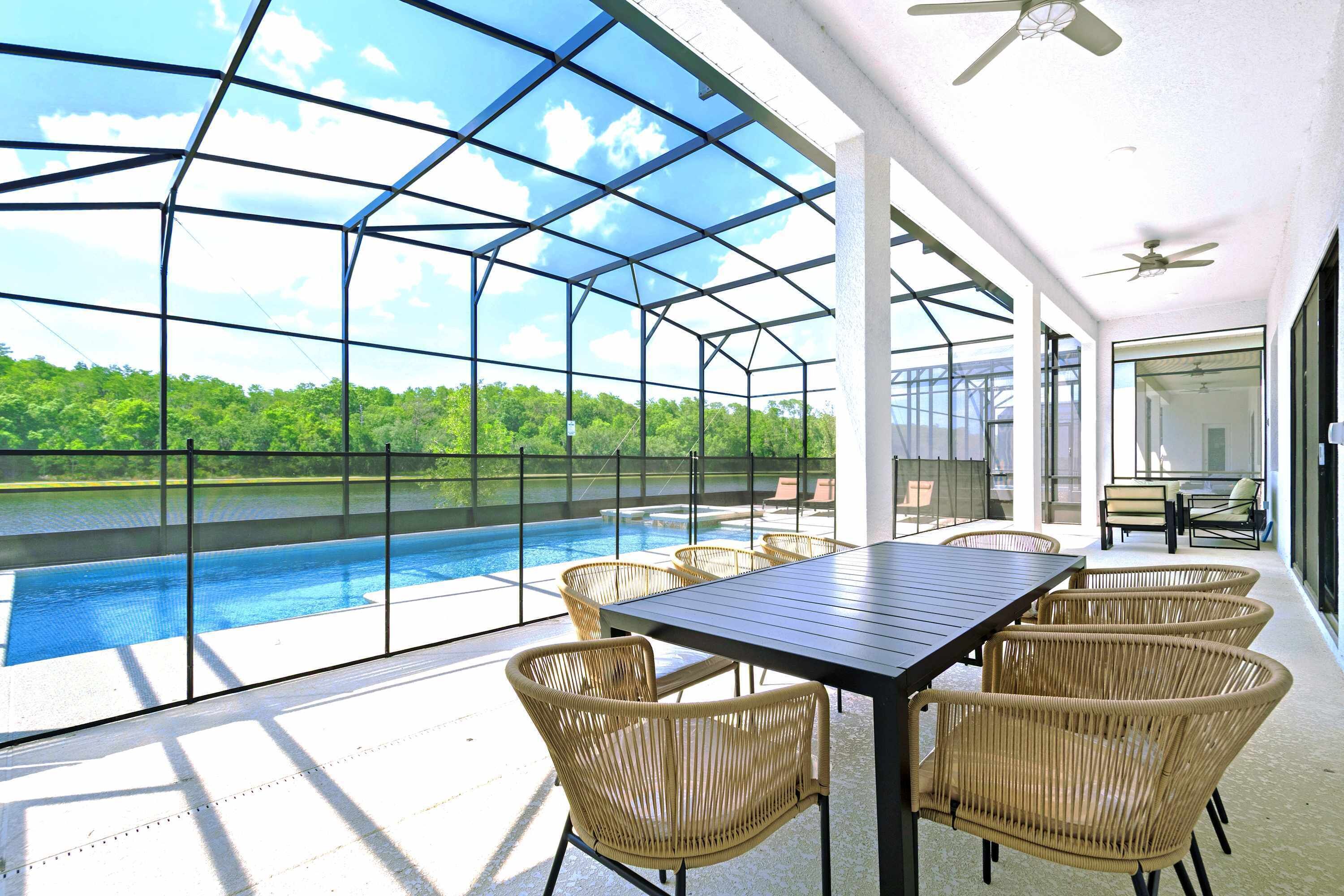 Un espace extérieur abrité comprenant une piscine, des fauteuils en osier et une table.