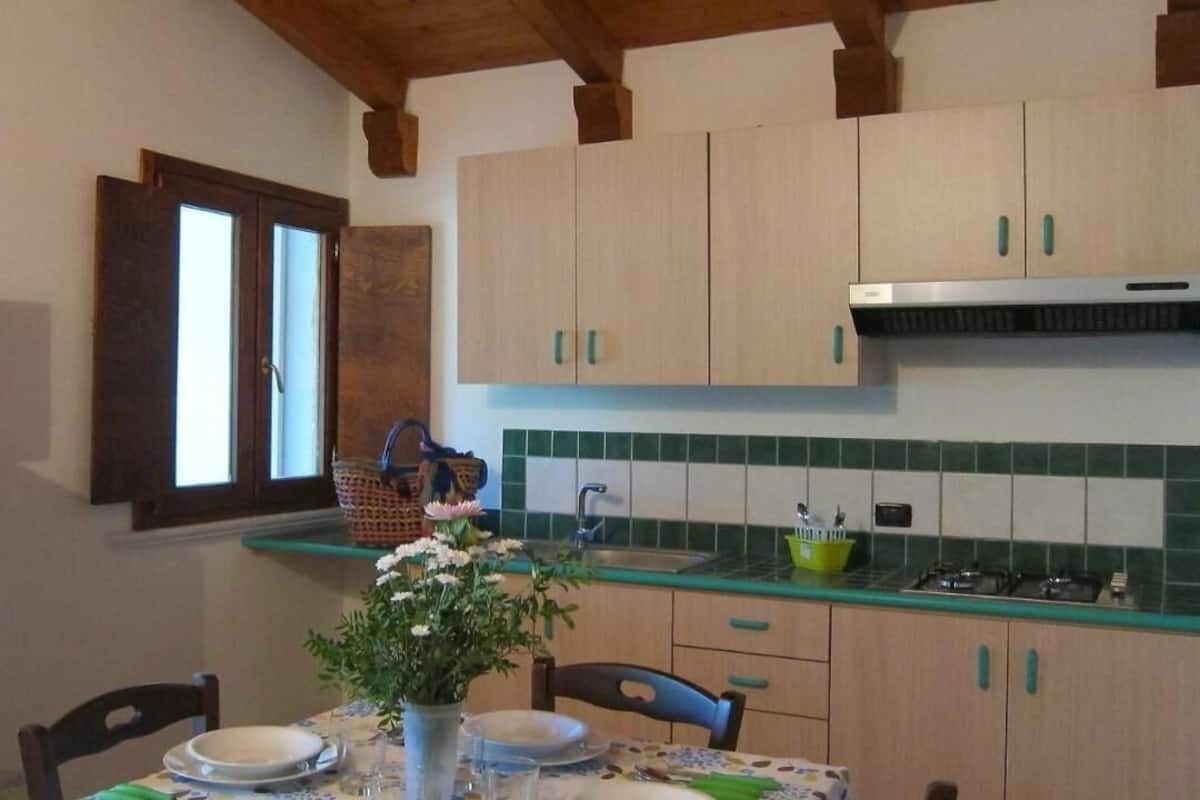 A kitchen with wooden cabinets, a window, a sink, and a table set for dining.