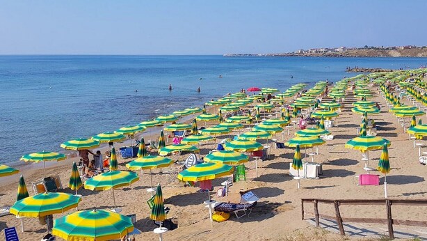 A beach with numerous umbrellas and sun loungers, a clear sky, and a calm sea. - Tucano Apartment Club Resort (Isola di Capo Rizzuto)