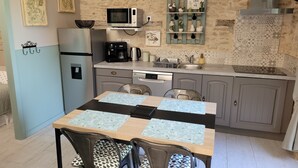 A compact kitchen with a dining area, equipped with a refrigerator, microwave, coffee maker, and a sink.