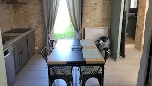 A dining area with a table, chairs, and a view through a window with curtains.