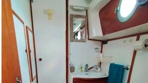 Une petite salle de bain comprenant des toilettes, un lavabo, un miroir et une petite fenêtre.