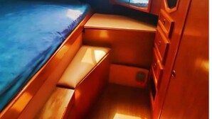 Une cabine compacte équipée d’un lit superposé, d’un petit coin salon et d’une fenêtre donnant sur l’extérieur.
