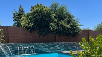 A swimming pool with a stone wall and a brick wall in the background.