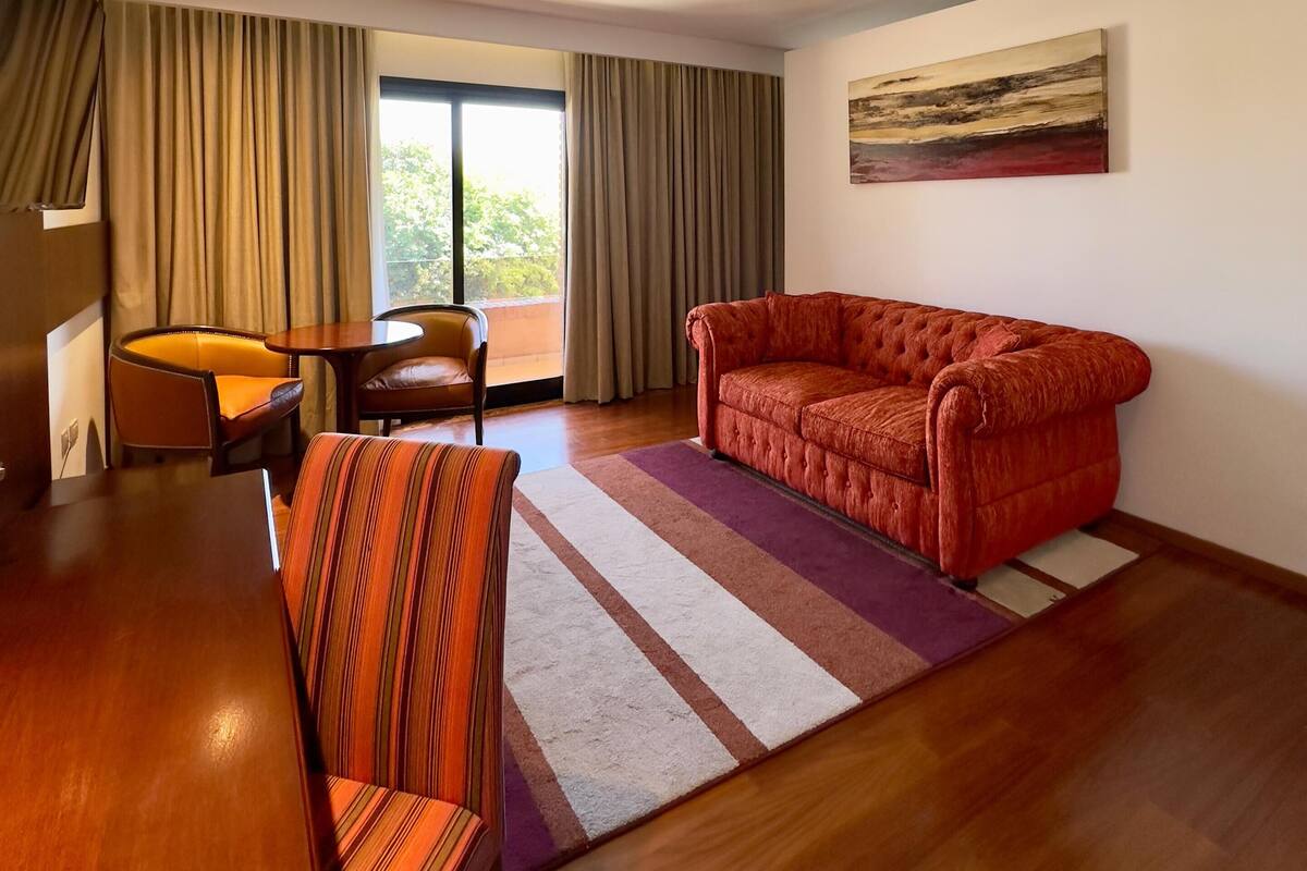 A modern living room with a red sofa, striped armchair, and a dining table.