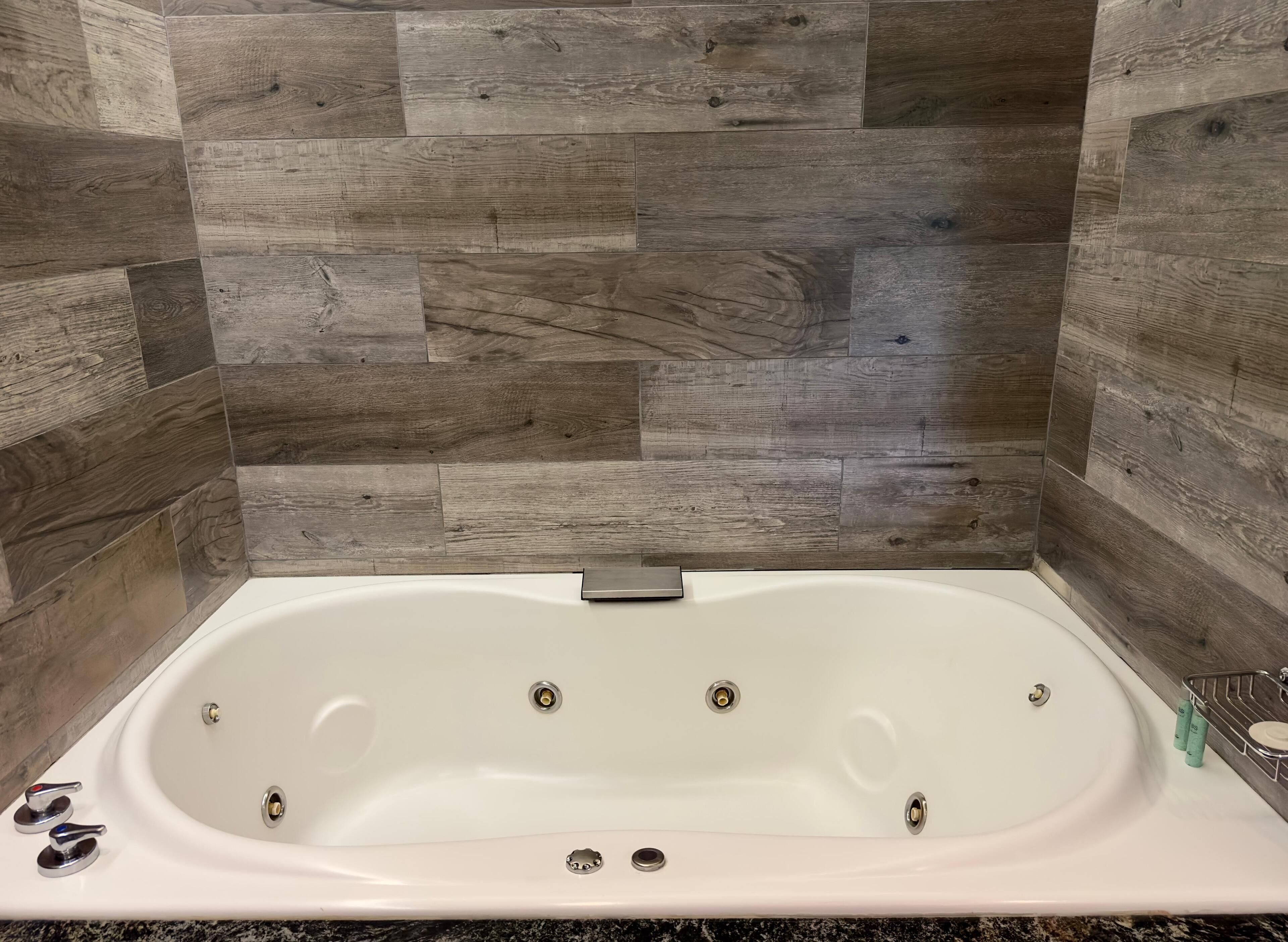 Une salle de bain avec une baignoire sur pieds, un comptoir en granit et un panneau mural en bois.