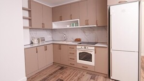 A kitchen with beige cabinets, a white refrigerator, a stove, and a sink.