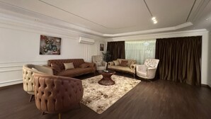 A spacious living room with a large brown sofa, a tufted armchair, and a coffee table.