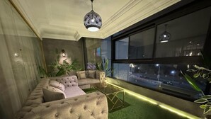 A modern living room with a sectional sofa, a glass coffee table, and a view of the city at night.