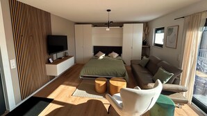 Una camera da letto moderna con un letto, un divano, una TV e un'ampia finestra.