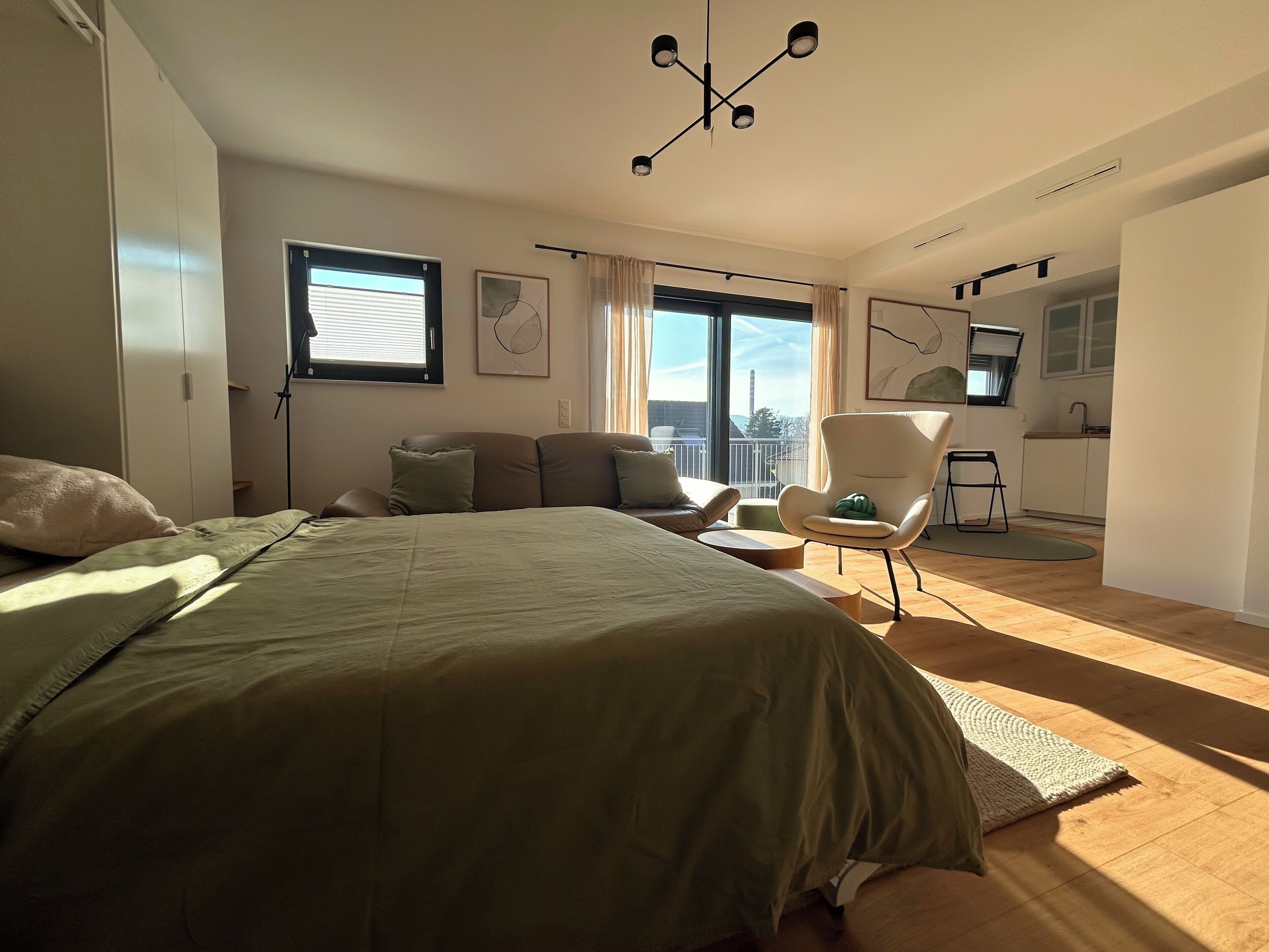 Stilvolles Studio mit viel Tageslicht, gemütlichem Bett, Sofa & Lounge-Sessel.