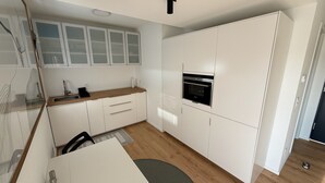 Una cucina moderna con mobili bianchi, un piano di lavoro in legno e un forno integrato.