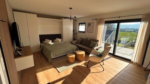 Una camera da letto moderna con un letto, un divano, una TV e un balcone con vista.