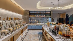 Ein modernes Frühstücksbuffet mit vielfältigen Speisen, einer Kaffeestation und einer dekorativen Wand mit Regalen.