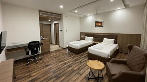 Ett hotellrum med två sängar, ett skrivbord, en stol och ett litet bord.
