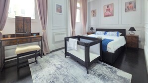 A bedroom with a bed, bedside tables, a desk, a chair, and a window with curtains. - City Home Paddington by Kravens (London)