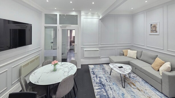 A modern living room with a marble table, grey sofa, and a large flat-screen TV. - City Home Paddington by Kravens (London)