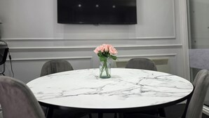 A conference room with a round marble table, a vase with pink flowers, and a flat-screen TV on the wall. - City Home Paddington by Kravens (London)
