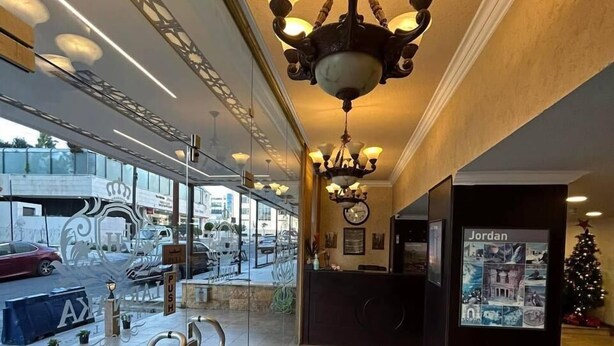 A lobby with a chandelier, a reception desk, and a glass wall with a 'PUSH' sign. - Larnaka Hotel (Amman)