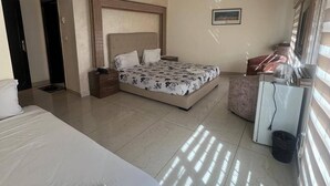 A hotel room with a large bed, a smaller bed, a desk, and a TV. - Larnaka Hotel (Amman)