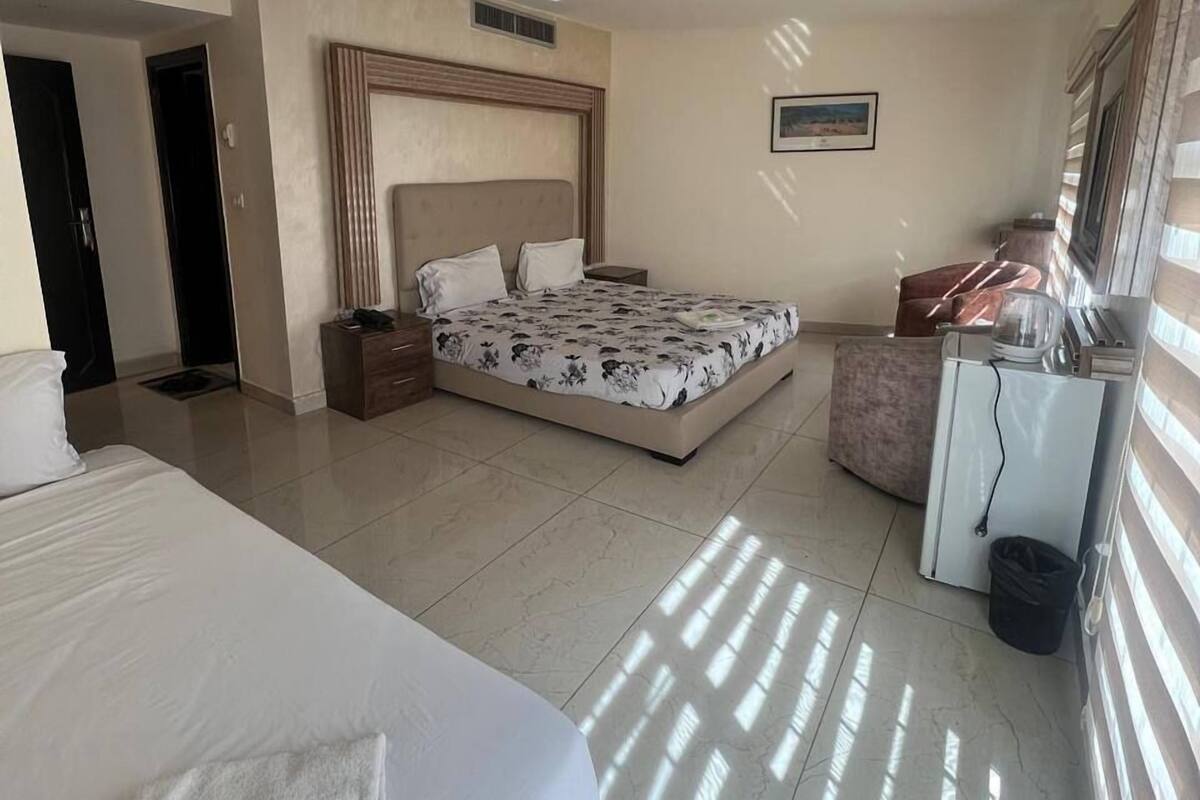 A hotel room with a large bed, a smaller bed, a desk, and a TV.