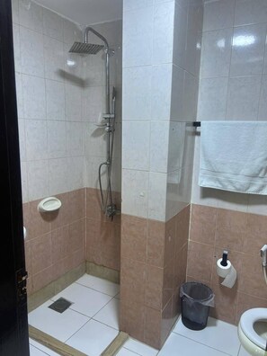 A small bathroom with a shower, toilet, and sink. - Larnaka Hotel (Amman)