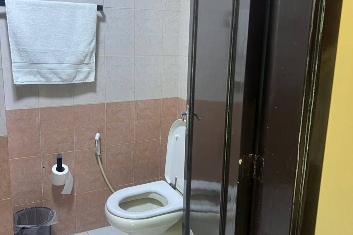 A bathroom with a toilet, a trash bin, and a towel hanging on a rack.