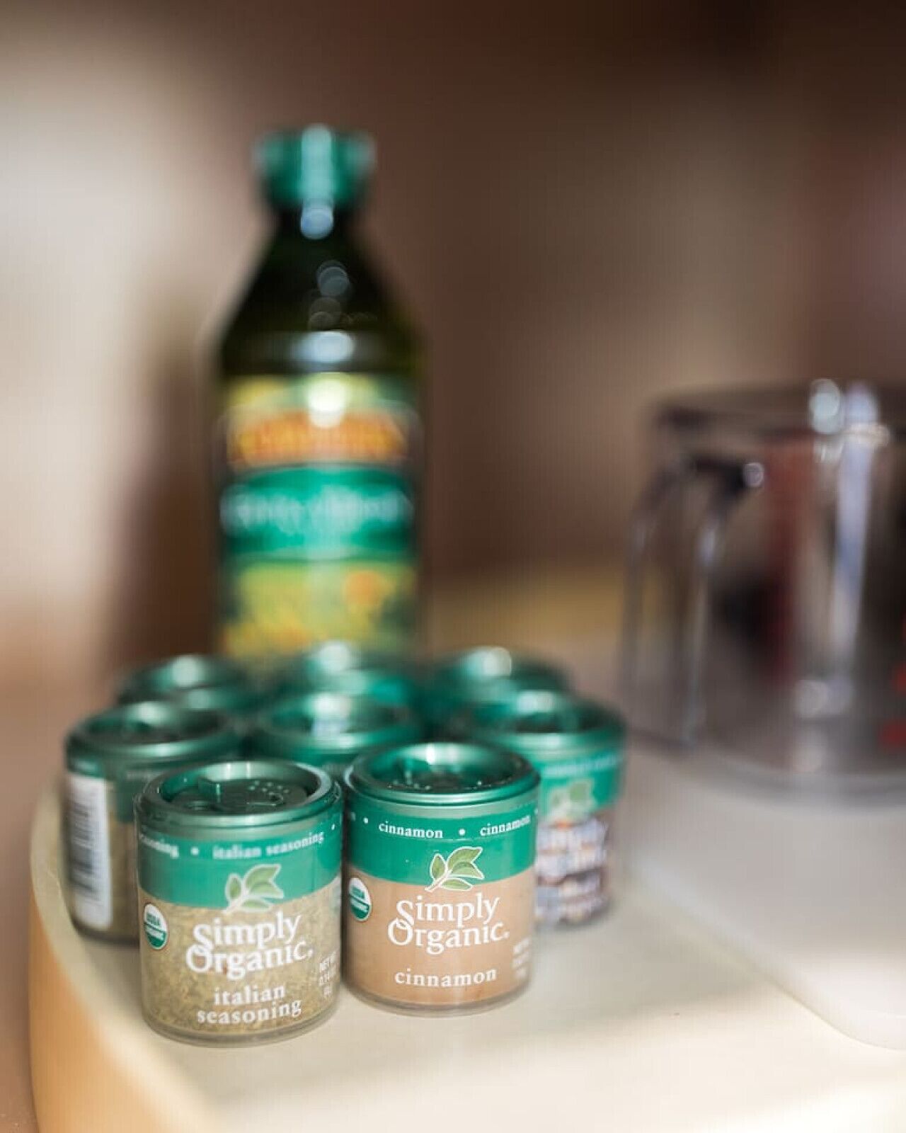 Eine Auswahl von Gläsern mit Simply Organic italienischen Kräutern und Zimt auf einem Regal.