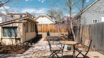 Enjoy outdoor dining on the patio surrounded by a small tree and a wooden deck.