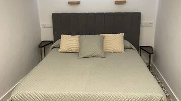 A bedroom with a bed, two bedside tables, a headboard, and a patterned floor.