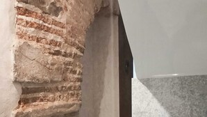 Une pièce avec un mur en pierre, un sol à motifs et un plafond blanc.