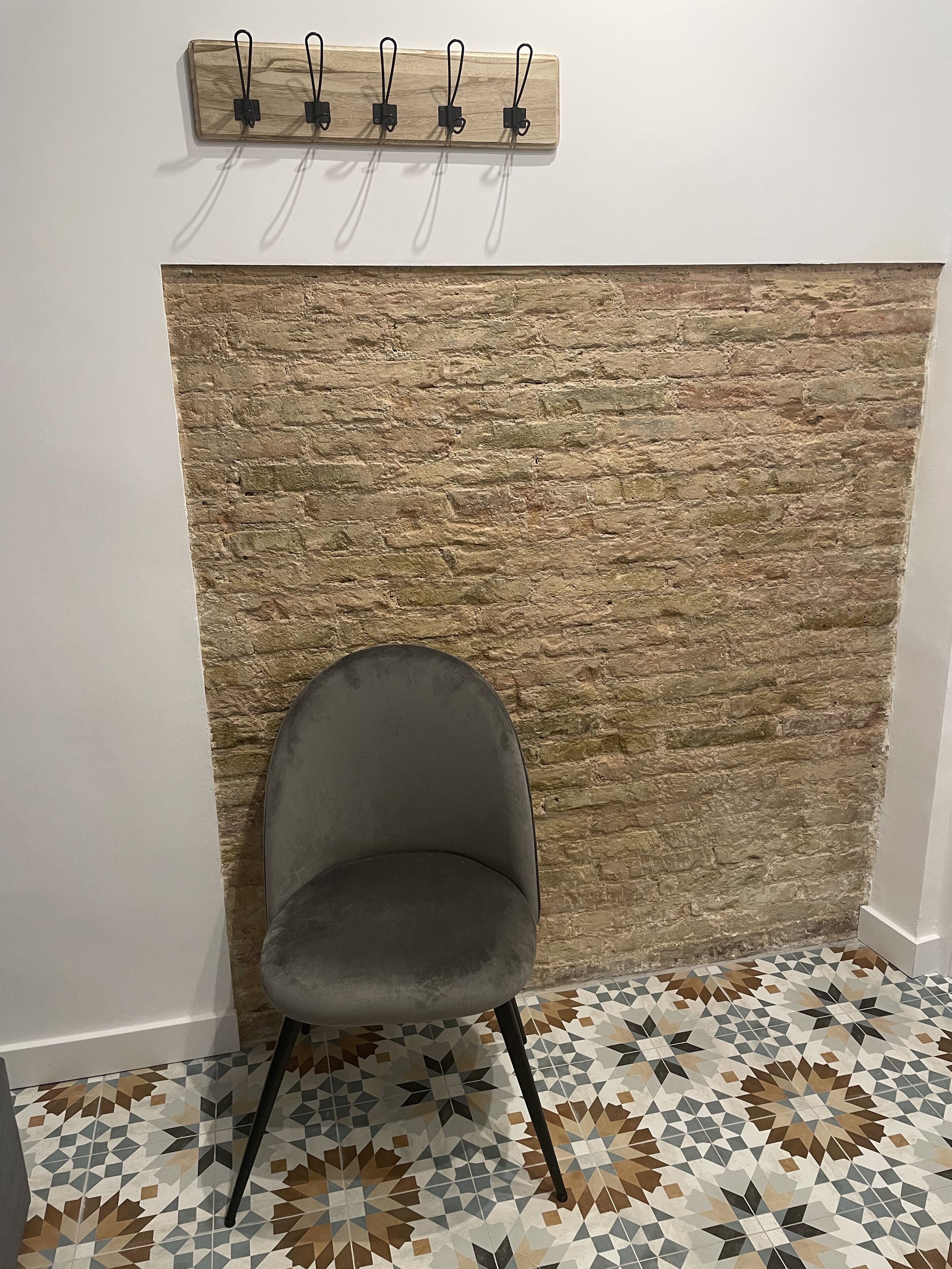 Uma cadeira em frente a uma parede texturizada com piso de padrão geométrico.