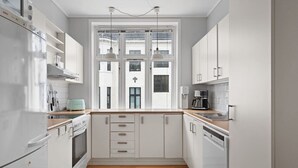 Eine moderne Küche mit weißen Schränken, einer Holzarbeitsplatte und einem Fenster mit Blick auf Gebäude.
