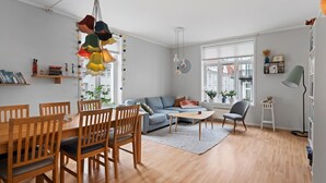 Ein modernes Wohnzimmer mit Essbereich, einer Couch, einem Couchtisch und einem Bücherregal.