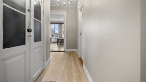 A hallway with white walls, a wooden floor, and a chandelier. - Experience the luxury lifestyle 100m from Bryggen! (Bergenhus)