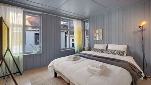 A bedroom with a bed, a bedside table, a lamp, and a window with curtains.