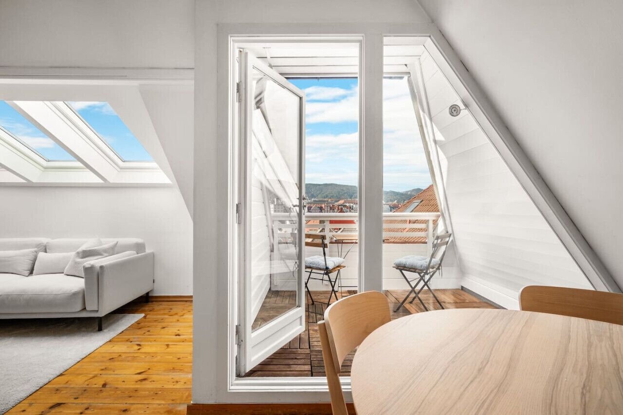 Ein modernes Schlafzimmer im Loft-Stil mit Oberlichtern, einer Couch, einem Esstisch und Blick auf die Landschaft.