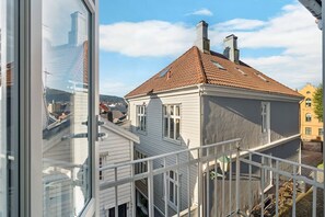 Ein weißes Gebäude mit rotem Ziegeldach und mehreren Schornsteinen, aufgenommen von einem Balkon mit weißer Brüstung.