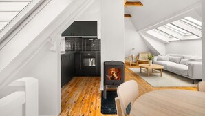 A modern loft with a kitchen, a fireplace, and a living area with a sofa and coffee table. - Bryggen  Historical Townhouse I Rooftop Views! (Bergenhus)