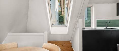 Un dormitorio estilo loft moderno con tragaluces, piso de madera y vista al exterior.