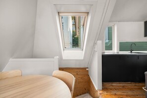 A modern loft bedroom with a skylight, a wooden floor, and a view of the outside.