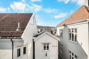 A narrow street with white buildings, a visible address sign, and a clear sky.
