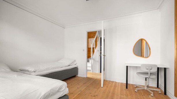 A modern bedroom with two beds, a desk, and a mirror. - Bryggen  Historical Townhouse I Rooftop Views! (Bergenhus)