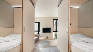 A modern hotel room with two beds, a flat-screen TV, and a small seating area with a sofa and coffee table. - The Double Date I  Architectural (Bergenhus)