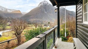Une cabane en bois dotée d’un balcon donnant sur un paysage montagneux.