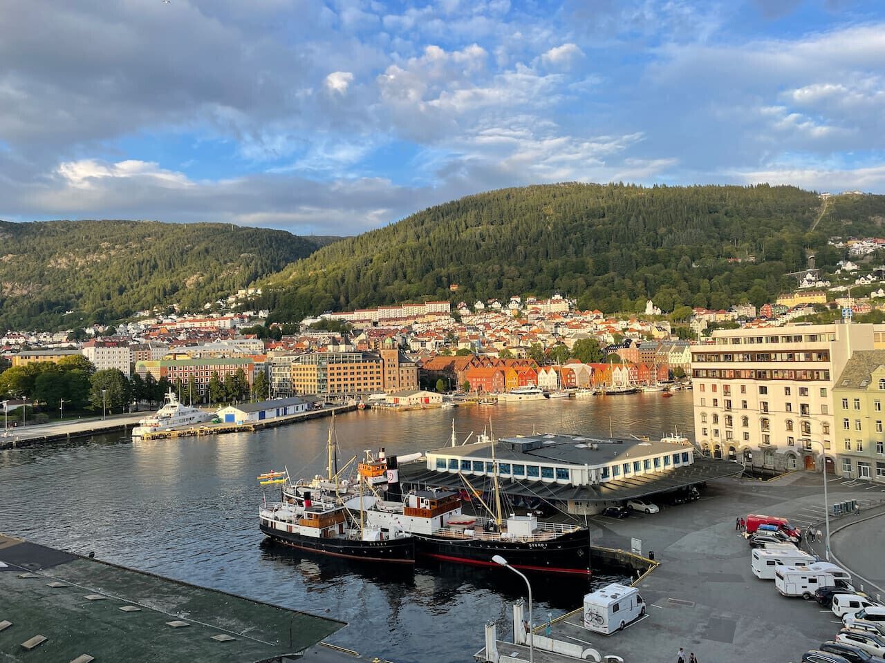 A harbor with boats, a large building with a white facade, and a densely built town in the background.