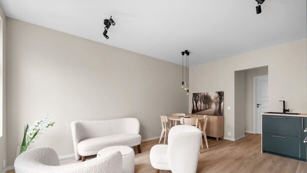 A modern living room with a sofa, chairs, a dining table, and a kitchen area. - Bergen Beds Apartments | Urban Escape (Bergenhus)
