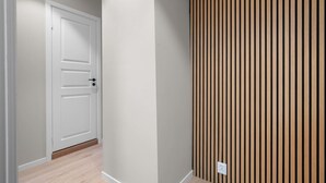 A hallway with a white door and a wooden panel wall. - Bergen Beds Apartments | Urban Escape (Bergenhus)